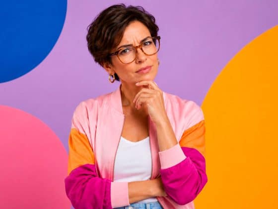 Comment fonctionne l’IA générative pour les images ? femme quadragénaire aux cheveux courts avec lunettes design et expression dubitative sur fond pastel pop coloré pour illustrer l’IA générative image