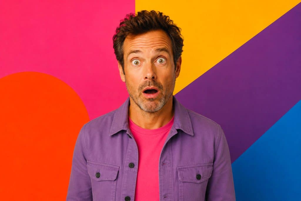 L’IA va-t-elle remplacer les designers graphiques ? homme quadragénaire surpris en veste rose sur fond pop coloré illustrant le débat IA vs designer graphique