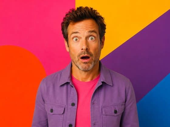 L’IA va-t-elle remplacer les designers graphiques ? homme quadragénaire surpris en veste rose sur fond pop coloré illustrant le débat IA vs designer graphique